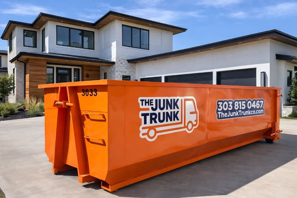 Branded orange Junk Trunk roll-off dumpster on a residential driveway